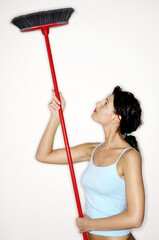 Woman cleaning ceiling with a broom