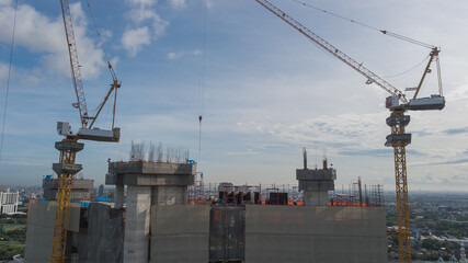 Large construction site including several cranes working on a building complex, with clear blue sky and the sun