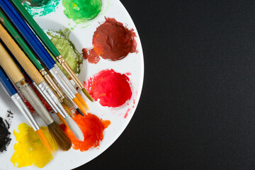 Top view of Colorful Watercolor palette and paintbrush  on a black background and copy space