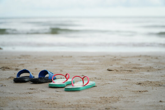 Two Pairs Of Slippers On The Beach