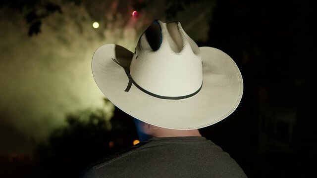 man in cowboy hat watching fireworks