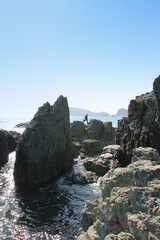 A man carry fishing tools and move around the magnificent rocks near the Oryukdo Skywalk in sunny day