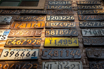 Collage of old, rusty and grungy car license plates over a brick wall illuminated by sun rays
