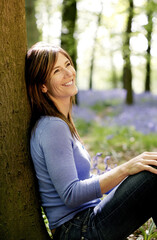 Woman smiling while leaning against a tree