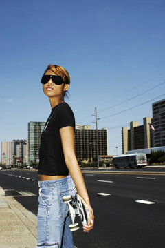 Woman with sunglasses holding a skateboard