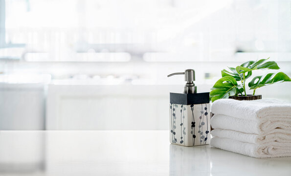 Ceramic shampoo, soap bottle and towels on counter over kitchen room background. White top table and copy space.