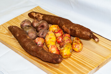 Raw yucca on the wooden table, Manihot esculenta. (Cassava raw tuber) with regional potatoes from the Andes at a market in Peru, Bolivia, Argentina, south america.