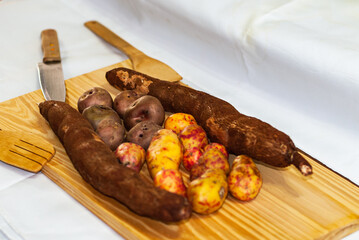 Raw yucca on the wooden table, Manihot esculenta. (Cassava raw tuber) with regional potatoes from the Andes at a market in Peru, Bolivia, Argentina, south america.
