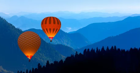 Deurstickers Blue mountain landscape with fog and pine forest at sunset -  Hot air balloon fly over blue mountains © muratart