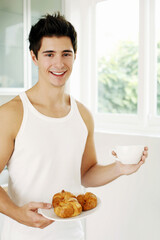 Man holding a plate of croissants and a cup of coffee