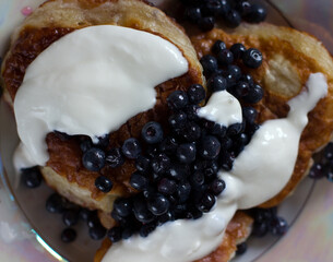 Pancakes with fresh blueberries in a plate with sour cream.