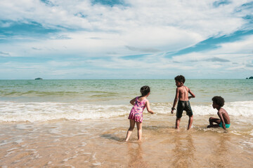Diversity group of Asian and African American children play on beach 