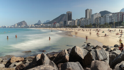 Long exposure Leme beach on a bright sunny day with blue sky with Copacabana neighbourhood scenery...