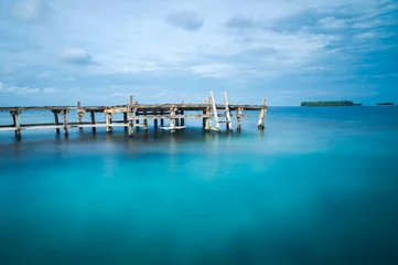 Fotobehang Wooden bridge on a blue sea. Long exposure photo © Dimatague