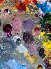 Artist's oil paint palette. Textured paint smudge closeup. Macro art color mixing. Purple, red, yellow colour shades swatches. Vibrant paint stain. Multicolor tones, Earth colors blend for painting. 