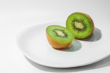 Fototapeta na wymiar Kiwi fruit's slices serve on a clean plate isolated in white background