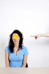 Finger pointing at a woman with a paper pasted on her face