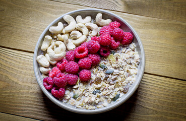Healthy Breakfast with muesli, cashew nuts and fresh raspberries on a wooden background. Copy space