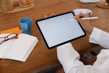 Cropped image of creative woman's hand holding/using a stylus pen to drawing on white blank screen...