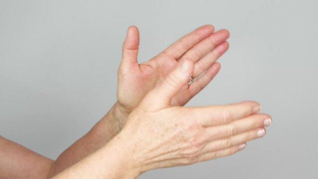 A senior female claps her hands in a rotating pattern.