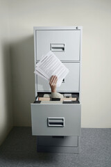 Businesswoman's hand coming out from opened cabinet holding papers