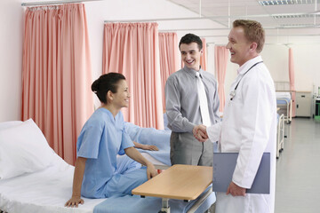 Man shaking doctor's hand, woman watching