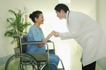 Woman on wheelchair, doctor holding her hands