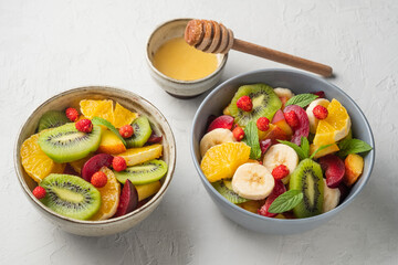 Concept of low calories delicious desserts. Summer fresh bowl with colorful fruit salad. Healthy natural organic food. Tasty sweet snack. Grey background. 