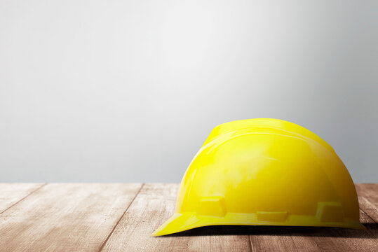 Hardhat On Wooden Table With A White Wall Background