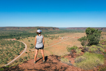 Fototapeta na wymiar Tourist observing the landscape. Woman wearing shorts, t shirt, trekking boots and a cap. Standing position. Hiking at Elsey national park, Victoria river, Northern Territory NT, Australia