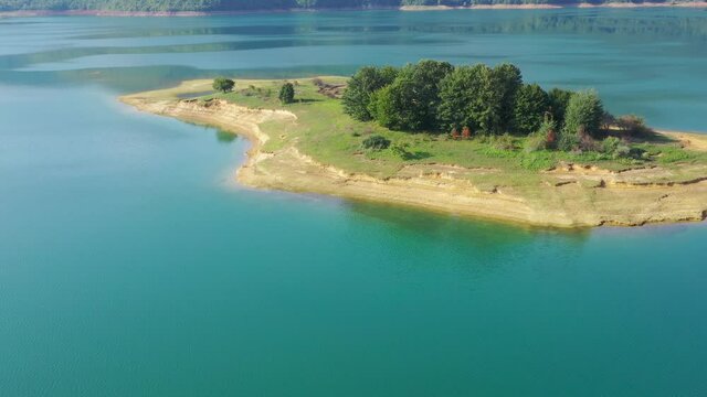 Rama Lake in Bosnia and Herzegovina with  eroded island with group of trees, Aerial dolly out shot