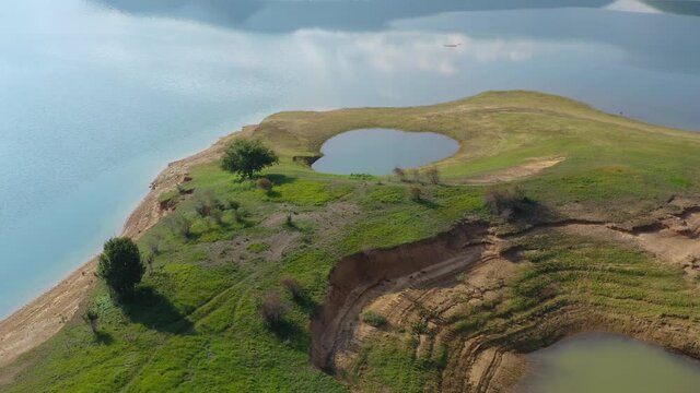 Small flooded pond in Rama Lake Bosnia and Herzegovina on a peninsula with eroded shore, Aerial flyover shot