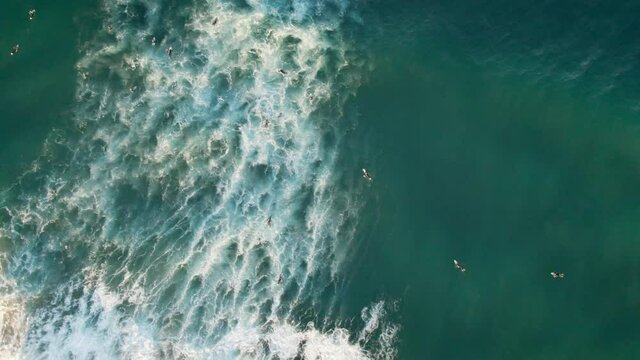 A group of surfers rowing against the crashing waves