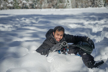 Fototapeta na wymiar Asian man tourist traveling to Yosemite in winter playing with the snow and capture the view with his professional camera