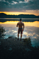 man stands on lake shore during sunrise