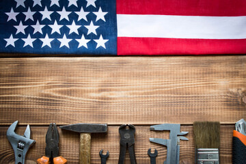 Labor day. American flag and various tools on a wooden table.