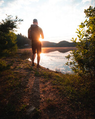 man stands on lake shore during sunrise