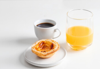 Black coffee bica and famouse pastel de nata (egg tart pastry) and orange juice on white background.Portuguese breakfast concept.