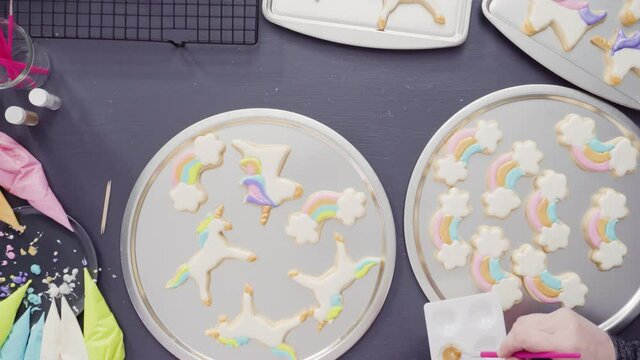 Flat lay. Step by step. Painting food glitter on top of unicorn sugar cookies with royal icing.