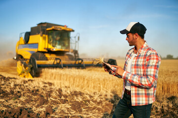 Precision farming. Farmer holding tablet for combine harvester guidance and control with modern automation system. Agronomist using online data management software generating yield maps at wheat field