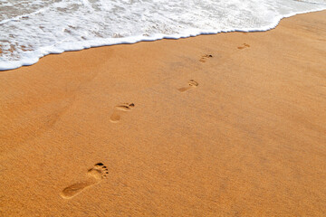 Footprints at sunset with golden sand. beach, wave and footsteps at sunset time