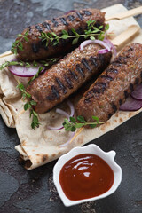 Close-up of bbq lula kebabs with lavash flatbread and dipping sauce, vertical shot, selective focus