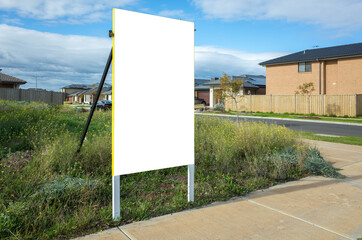 Blank white empty mockup template of a real estate sign at front of a lot of vacant land in a...