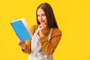 Young woman with recipe book on color background