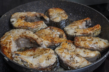 Fish steaks fried in a pan on an induction stove	
