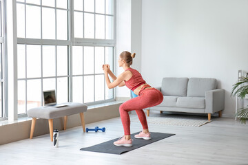 Sporty young woman with laptop training at home