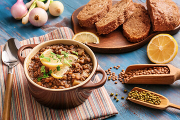 Pot of tasty lentils soup on table