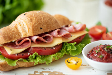 french croissant with ham, cheese, tomato and salad