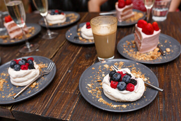 Sweet cakes with summer berries on a wooden table. Party, sweet table. Summer offer desserts in the restaurant.
