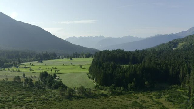 Ariel shot looking over seefeld village mountains tracking down into the vibrant green pines